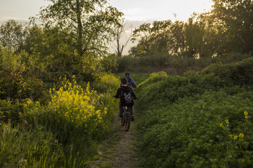 Bambini in bici al tramonto immersi nella natura