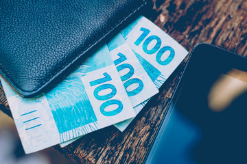 Money from Brazil. Real notes, Brazilian currency inside a black and cell wallet on the side....