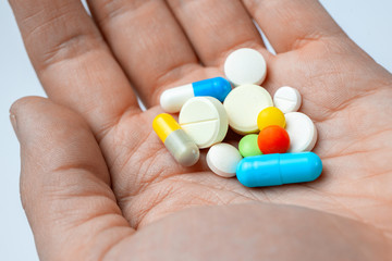 Many color pills and capsules in hand. closeup
