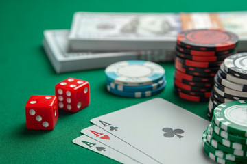 Concept of gambling in casino, sports poker. Playing cards with dice and colored chips with cash money dollars on green gaming table.