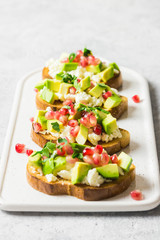 Avocado feta cheese pomegranate seeds crostini. Selective focus, space for text.
