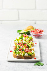 Avocado feta cheese pomegranate seeds crostini. Selective focus, space for text.