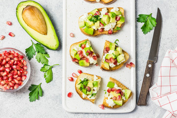 Avocado feta cheese pomegranate seeds crostini. Top view, space for text.