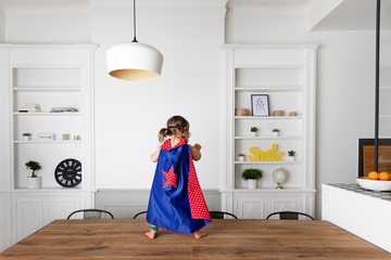 Toddler dressed up as superhero standing on kitchen table