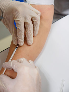 Close-up detail of a dermatologist injecting corticorsteroids into the forearm of a patient, vertical orientation. Healthcare and cosmetic surgery.