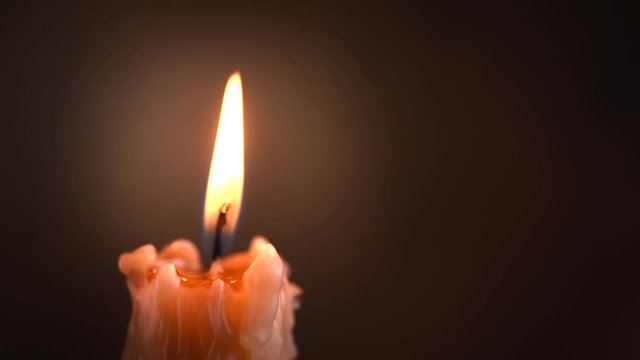 Candle flame closeup on dark background. Candle light border design. Melted wax candle burning at night. Slow motion 4K UHD video footage. 3840X2160