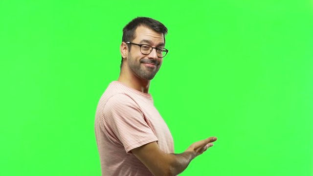 man pointing back and presenting a product  on green screen chroma key background