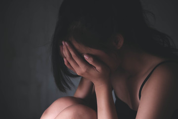 Sad depressed woman suffering from family life. women sitting in dark room cryng, palm close her face. Young beautiful women thinking how to solve problem.