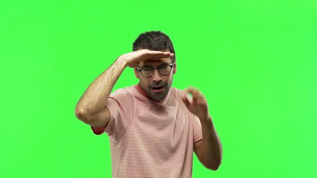 man looking far away with hand to look something  on green screen chroma key background