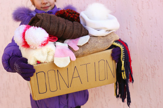 Girl holding donation box with warm winter clothes.