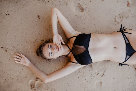 Top View On Beautiful Young Woman In Black Bikini Lying On Beach Sand