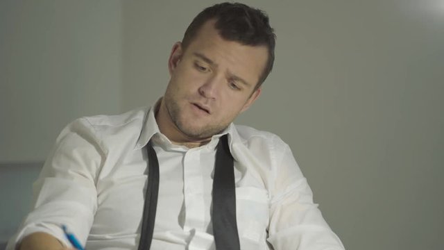 The guy detective in a white shirt listens to the interlocutor with a surprised face in his office