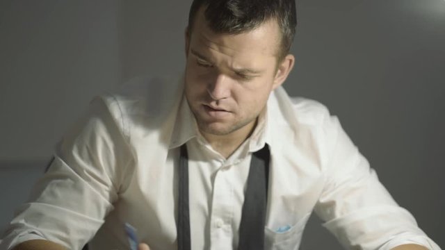 The guy detective in a white shirt listens to the interlocutor with a surprised face in his office