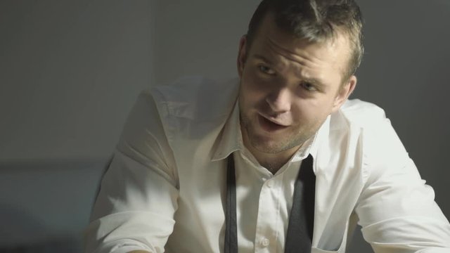 The guy detective in a white shirt listens to the interlocutor with a surprised face in his office