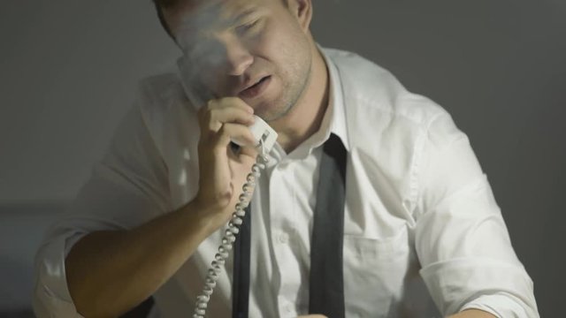 The guy detective in a white shirt listens to the interlocutor with a surprised face in his office