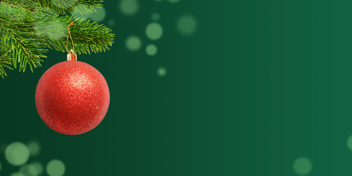 Red shiny ball for Christmas tree. Green background for holiday greeting text.