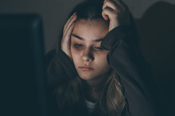 Teenager girl suffering internet cyber bullying scared and depressed cyberbullying. Image of despair girl humilated on internet by classmate. Young teenage girl crying in front of
