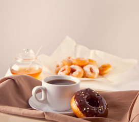 Fresh donuts with cup of coffee on the wooden table