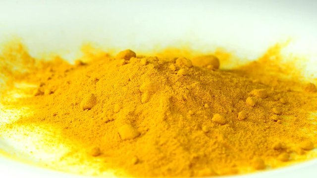 turmeric powder falling on a desk and on a weight and turn table
