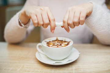 Obraz na płótnie Canvas Female hand pours sugar into coffee. wooden table background