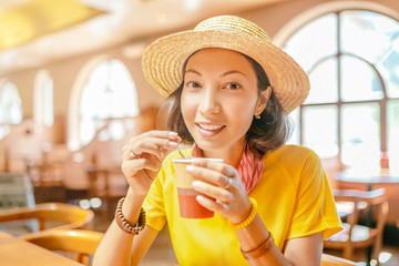 Young woman drinking coffee or tea from paper cup in cafe