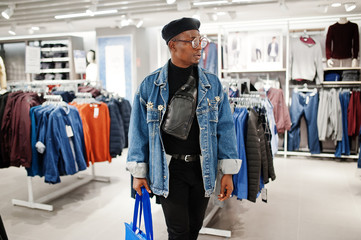 Stylish casual african american man at jeans jacket and black beret with fanny pack or waist bag...