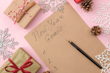 New Years goals 2019. Text on a piece of paper with a New Year's decor and a pen on a bright pink background.