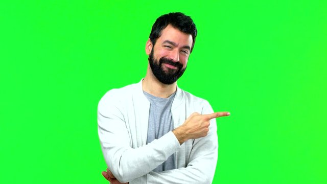 Man with beard on green screen chroma key background and pointing