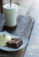 brownie cake with whipped cream and coffee on the table