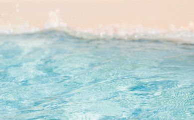 Fototapeta na wymiar Bokeh blurred soft azur sea water wave and light pure sand on the beach. Vacation theme background.