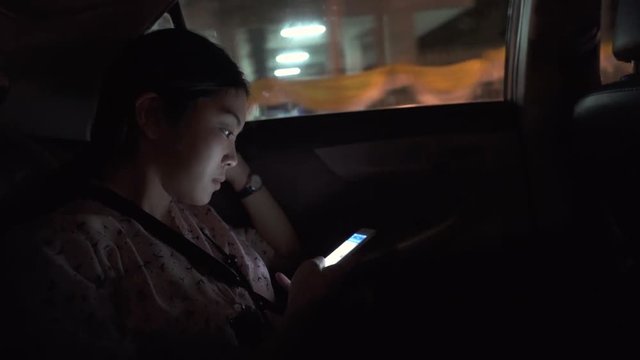 Young woman using phone for social networking on Taxi driver,Thailand