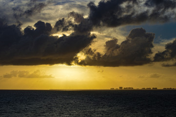 Sunset at sea off the coast on Miami FL USA with dramatic cloud cover and yellow tones