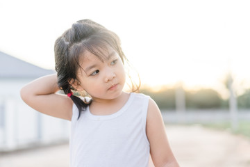 Little asian girl scratching an itch with hand outdoor.Kid's hand scratch itchy from allergy.Sensitive Skin, Food allergy symptoms, Irritation.
