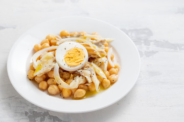 chick-pea with cod fish and boiled egg on white plate