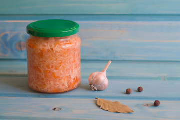 Sauerkraut with carrots in jars on a blue wooden background.