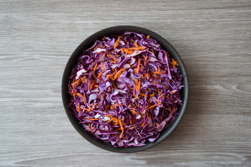Sliced purple cabbage and orange carrot in a pan on a wooden table.