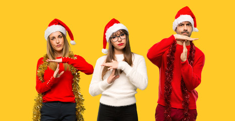 A group of people Blonde woman dressed up for christmas holidays making stop gesture with her hand to stop an act on yellow background