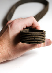 Obraz premium The old worn out rubber alternator belt in men's hand. The concept of car maintenance. Vertical photo
