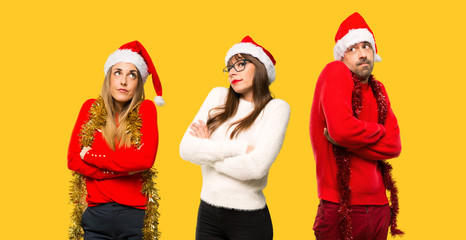 A group of people Blonde woman dressed up for christmas holidays making unimportant gesture while lifting the shoulders on yellow background