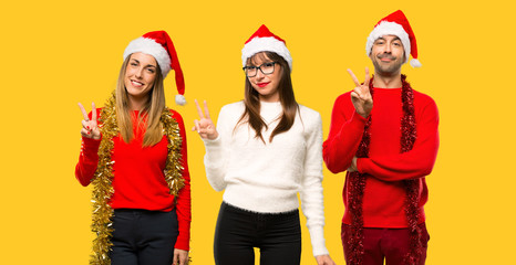 Fototapeta premium A group of people Blonde woman dressed up for christmas holidays happy and counting two with fingers on yellow background