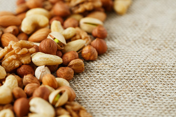 Mix of nuts lying on a background of brown cloth burlap.
