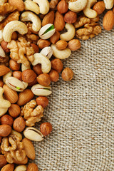 Mix of nuts lying on a background of brown cloth burlap.