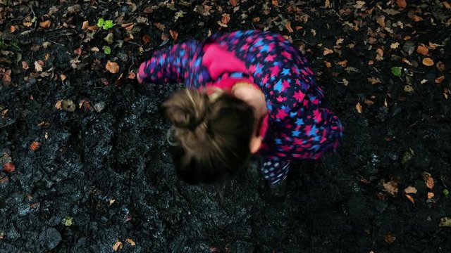 Young girl playing in a muddy puddle in the Autumn time