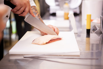 Chef slicing duck breast in kitchen restaurant. Meat preparation