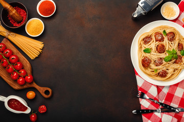 Spaghetti pasta with meatballs, cherry tomato sauce and cheese on rusty background.