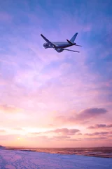 Wall murals Pale violet Airplane in the sky over the snowy beach at sunset