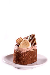  A biscuit cake is sprinkled with cocoa with chocolate cream, a heart of white chocolate, a slice of chocolate tile  and a delicious waffle isolated