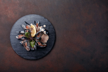 Seafood mussels in cream sauce with lemon and basil on a stone and rusty background