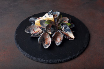 Seafood mussels in cream sauce with lemon and basil on a stone and rusty background