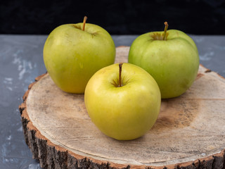 Three green apples on a wooden platter, close-up